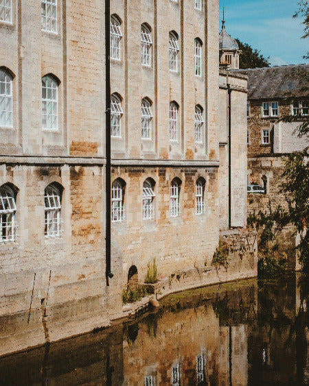 Stone building with arched windows reflected in water